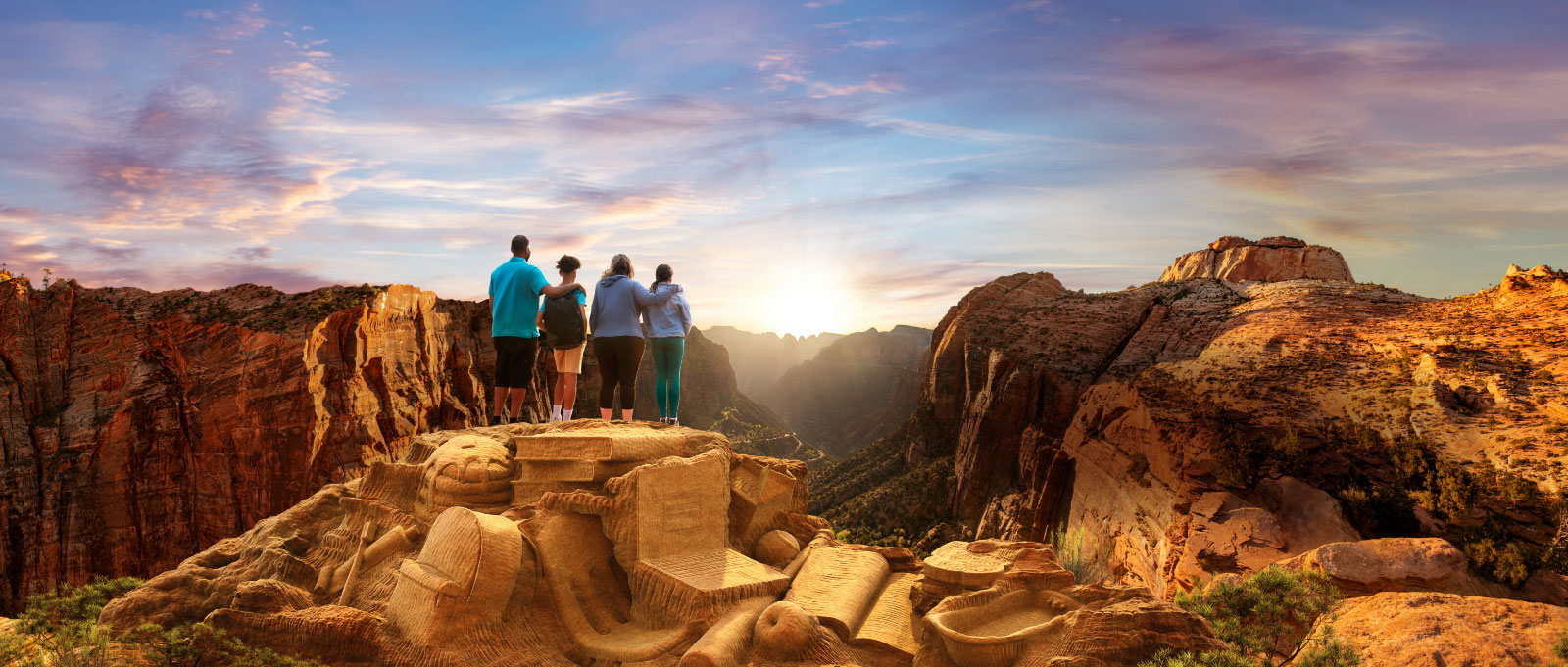 Image of family standing on a mountaintop watching the sun set